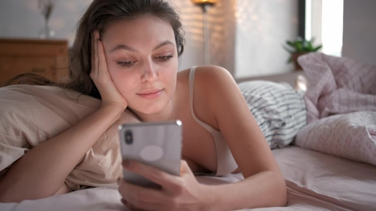 Free Stock Video Relaxed Woman On Bed Looking At Her Smartphone Live Wallpaper