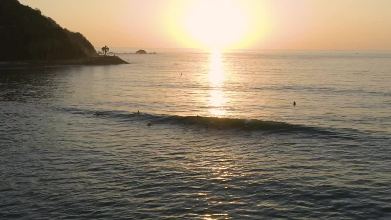 Free Video Stock surfing waves near a shoreline at sunset Live Wallpaper