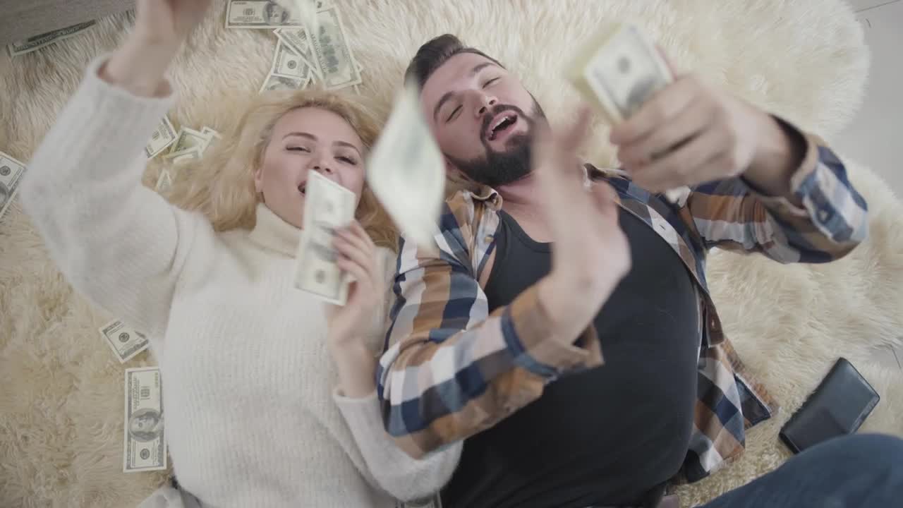 Free Video Stock top view of rich couple on rug laying in money Live Wallpaper