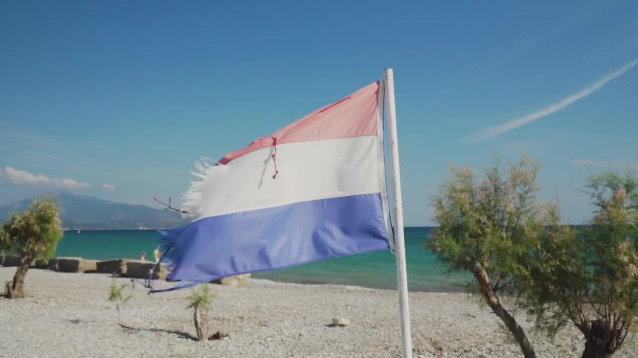 Free Video Stock torn red white and blue flag waving on a beach Live Wallpaper