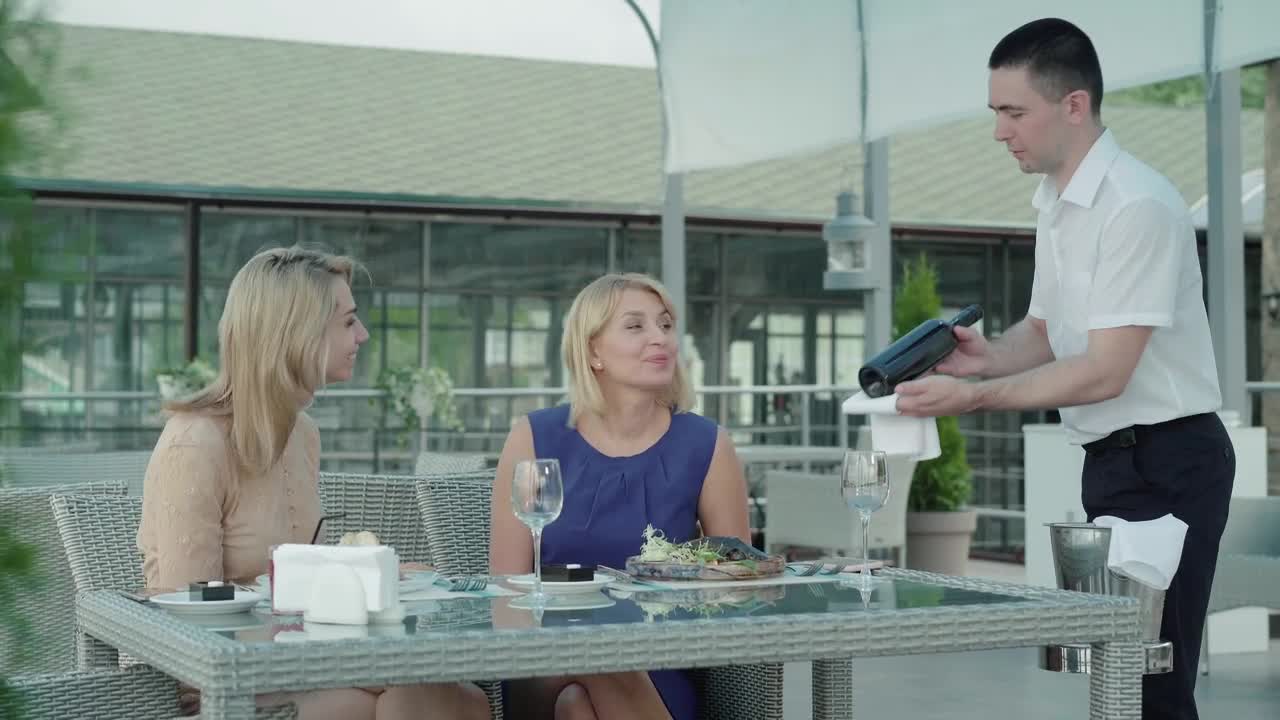  Stock Footage Waiter Presents Wine To Women Dining In Outdoor Restaurant Live Wallpaper