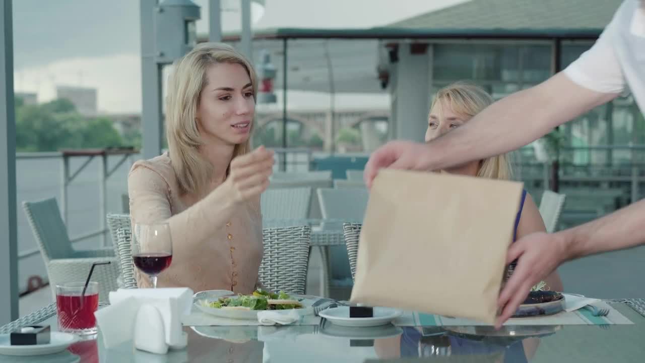   Stock Footage Waiter Gives To Go Bag To Women Dining In Outdoor Restaurant Live Wallpaper