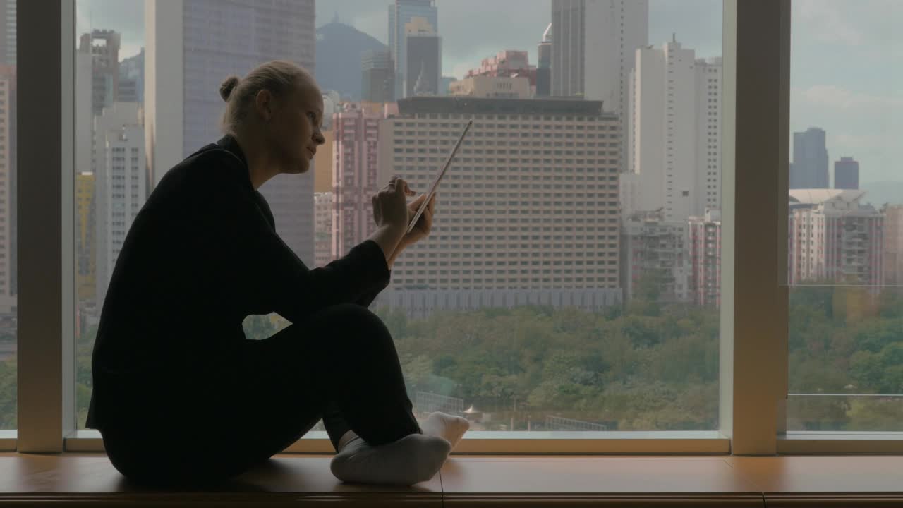 Stock Footage Woman Sitting By A Window With A Tablet Live Wallpaper Free