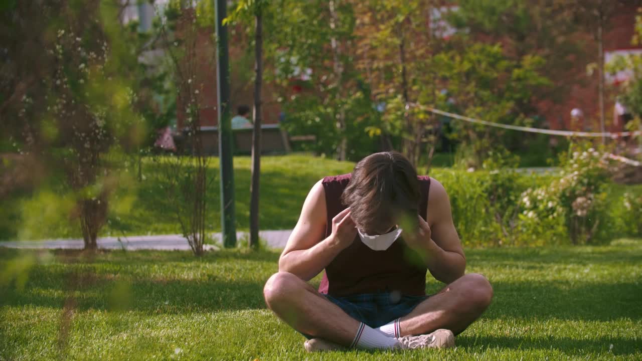 Stock Footage Young Man Sitting In The Park Puts On A Face Live Wallpaper Free