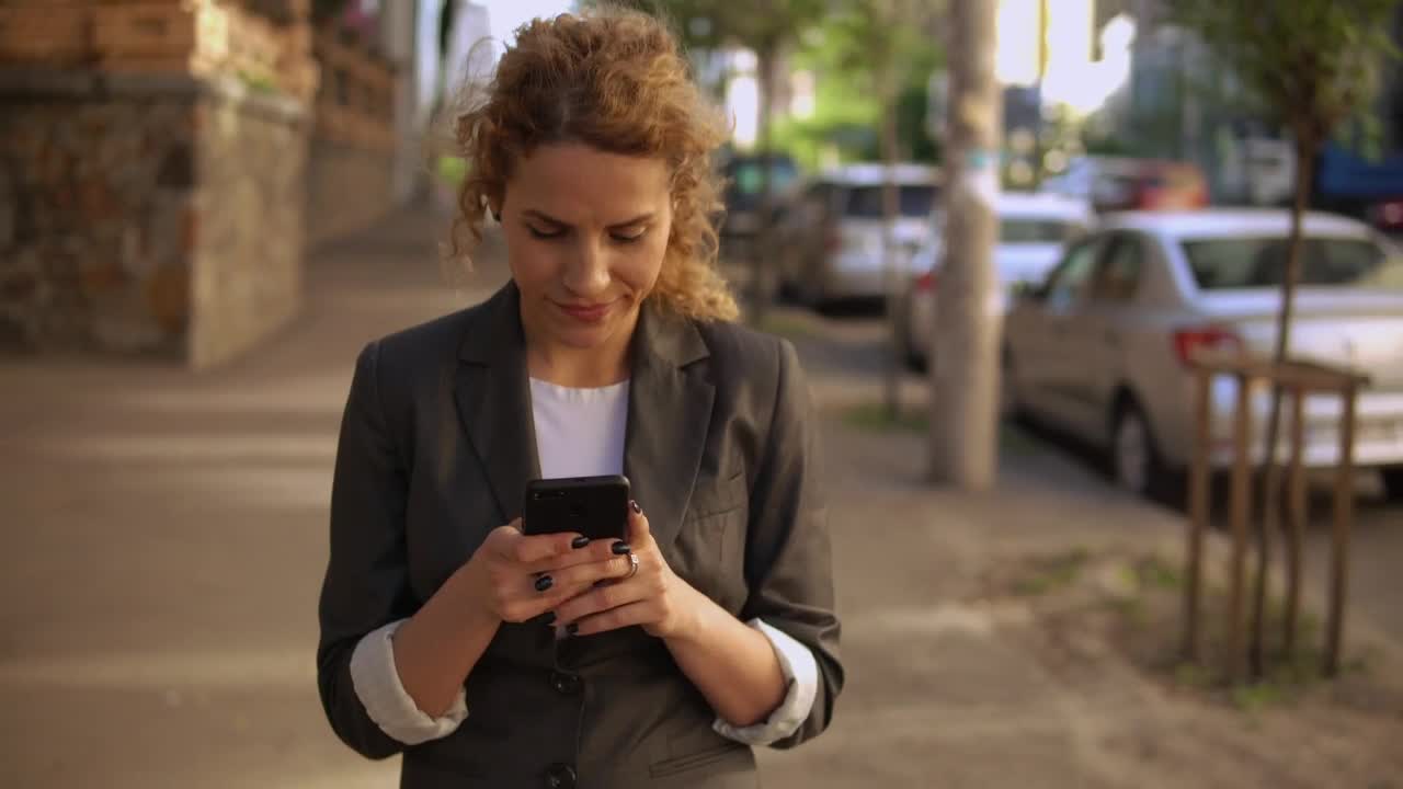 Stock Footage Woman Walking Down The Street Watching Her Cell Phone Live Wallpaper Free