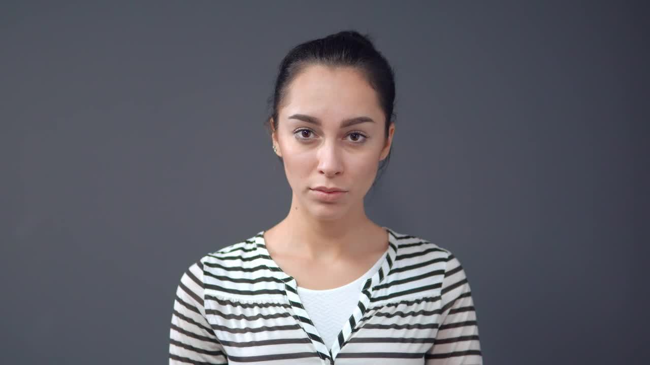 Stock Footage Young Sad And Serious Woman On A Gray Background Live Wallpaper Free