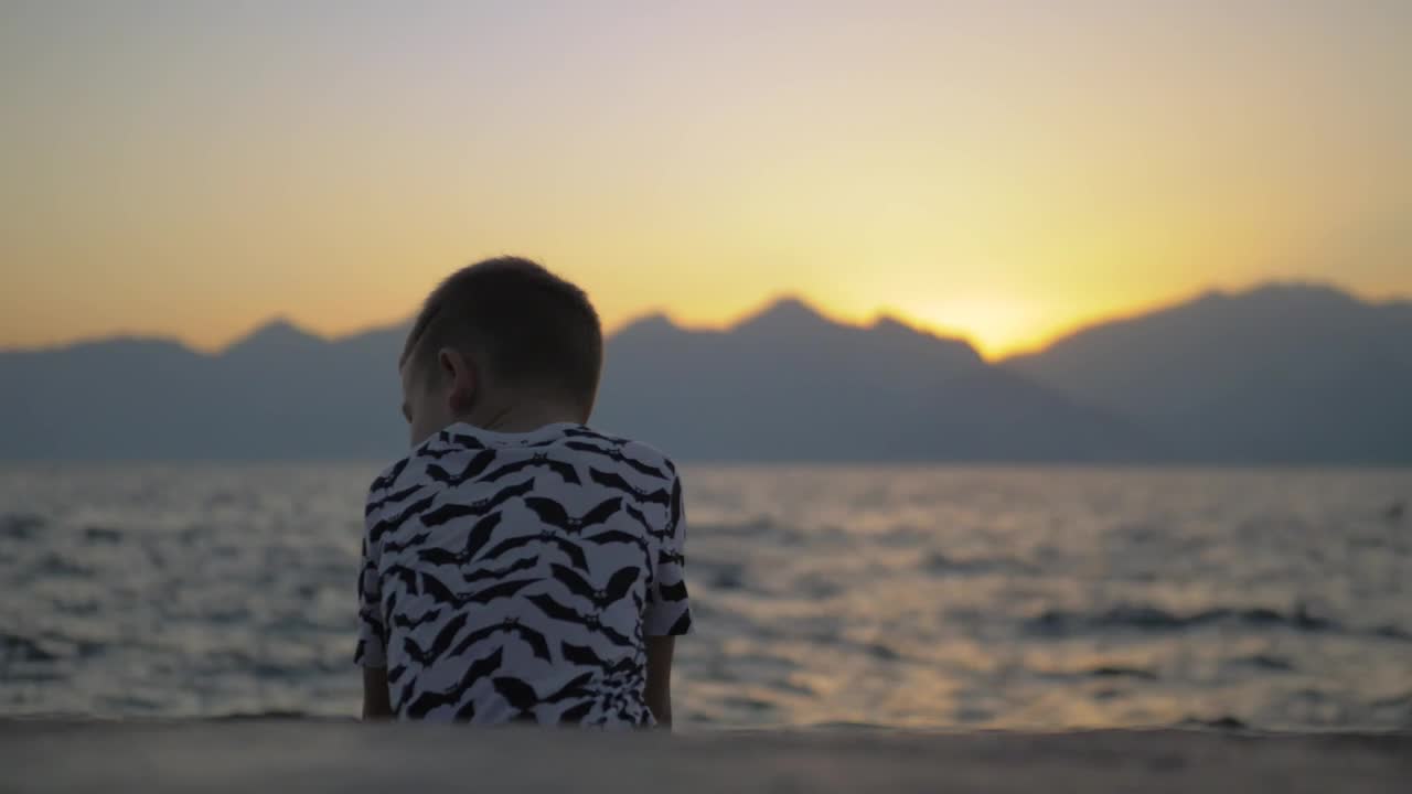 Stock Video Lonely Boy Sitting On The Seashore Animated Wallpaper