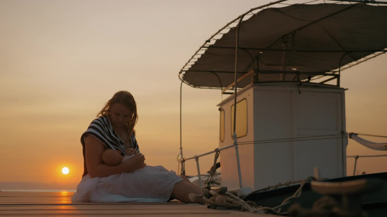 Stock Video Mother Sitting By A Boat With Her Bab Animated Wallpaper