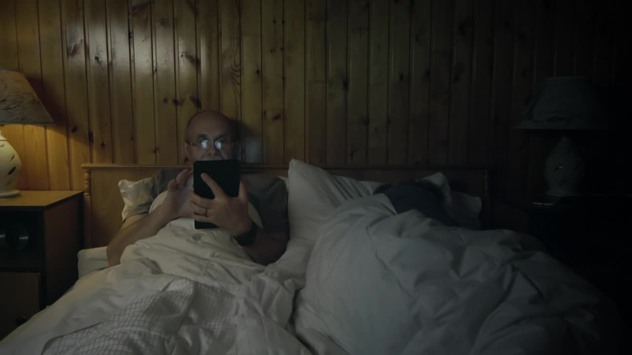 Stock Video Man Watching The Tablet In The Bedroo Animated Wallpaper